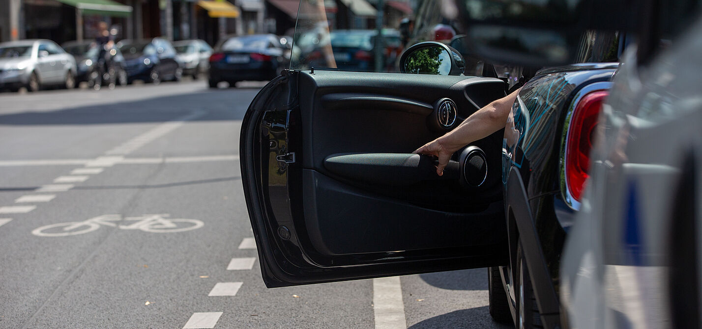 Dooring - eine Gefahr für Radfahrende Plötzlich geöffnete Autotür im Straßenverkehr – typische Gefahrensituation für vorbeifahrende Radfahrende.
